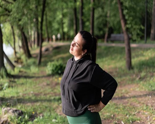 Person stretching and resting eyes outdoors in a green park