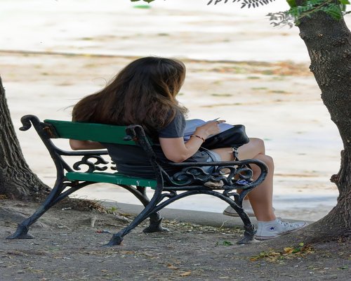 Person sitting outdoors on a bench away from screens taking a mindful break
